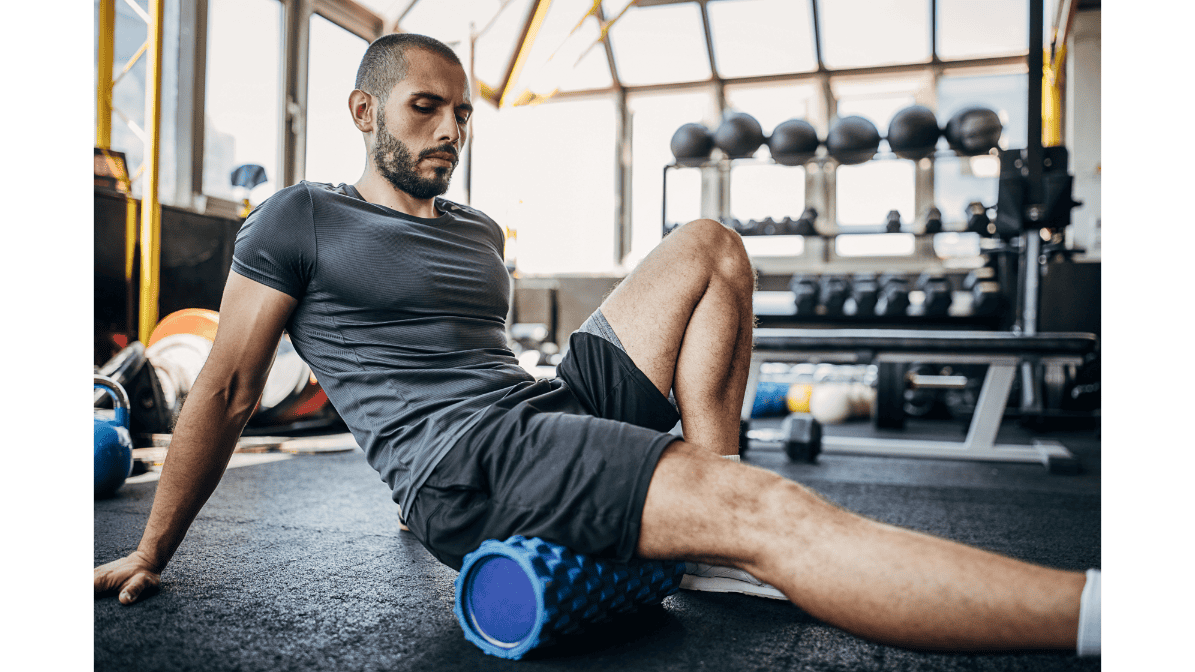 Man using a foam roller on his leg muscles in a gym for muscle recovery and pain relief