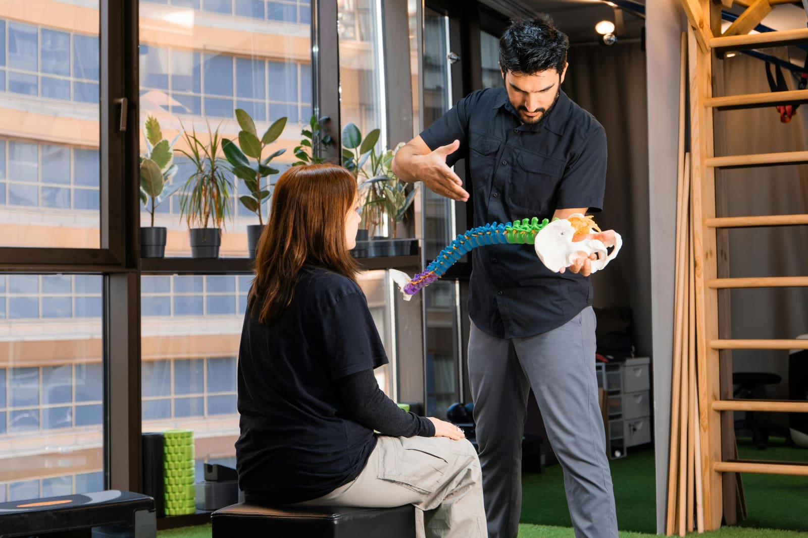 Practitioner demonstrating a spine anatomy model to a patient
